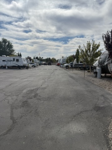 The paved drive through High Desert RV Park lined with RVs and trees